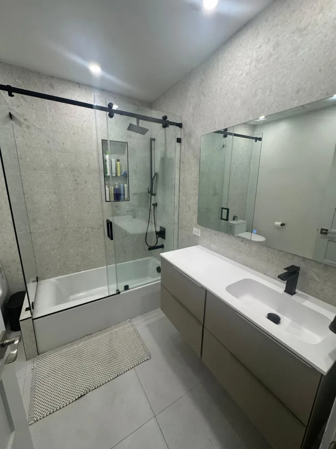 Stone-tiled bathroom with sliding-glass tub shower and modern floating vanity