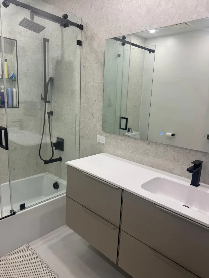 Stone-tiled bathroom with tub-shower combo, black fixtures, and floating vanity
