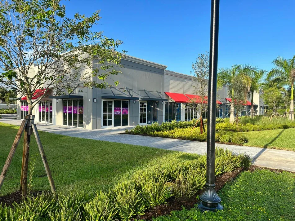 Multi-tenant retail building with coming-soon storefronts and lush landscaping