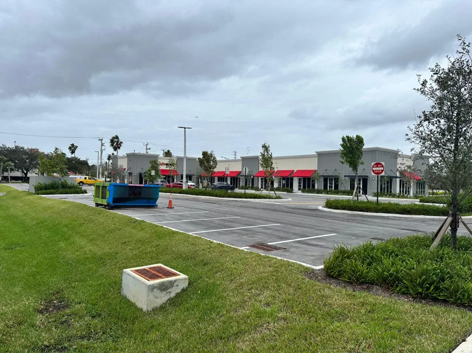 Row of retail storefronts with red awnings and landscaped walkway in Miami, FL