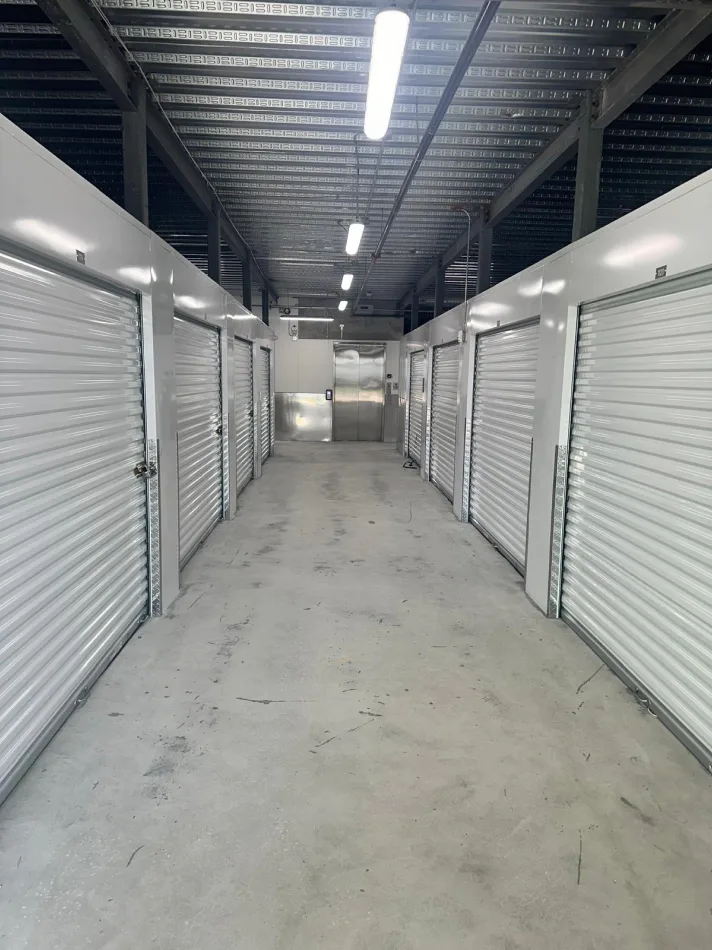 Interior corridor of self-storage facility with rows of white roll-up unit doors
