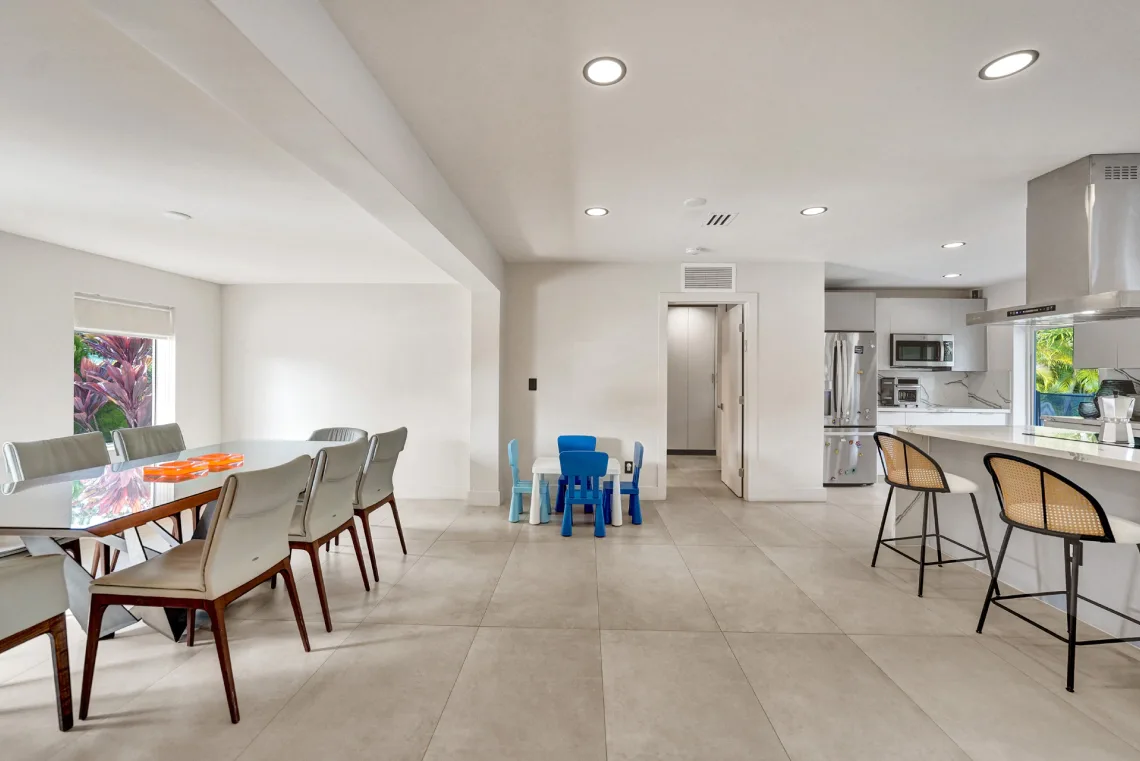 Spacious dining room with glass table adjoining an open modern kitchen in Miami, FL