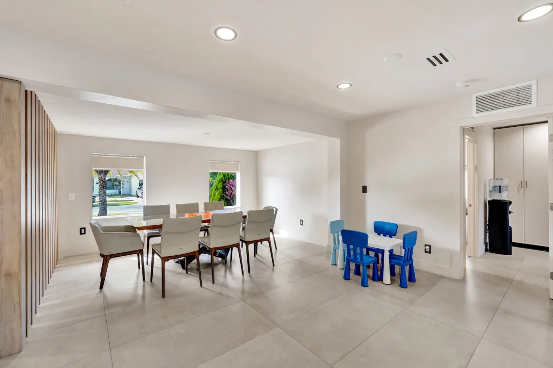 Open dining room with glass table, upholstered chairs, and a small children's play table