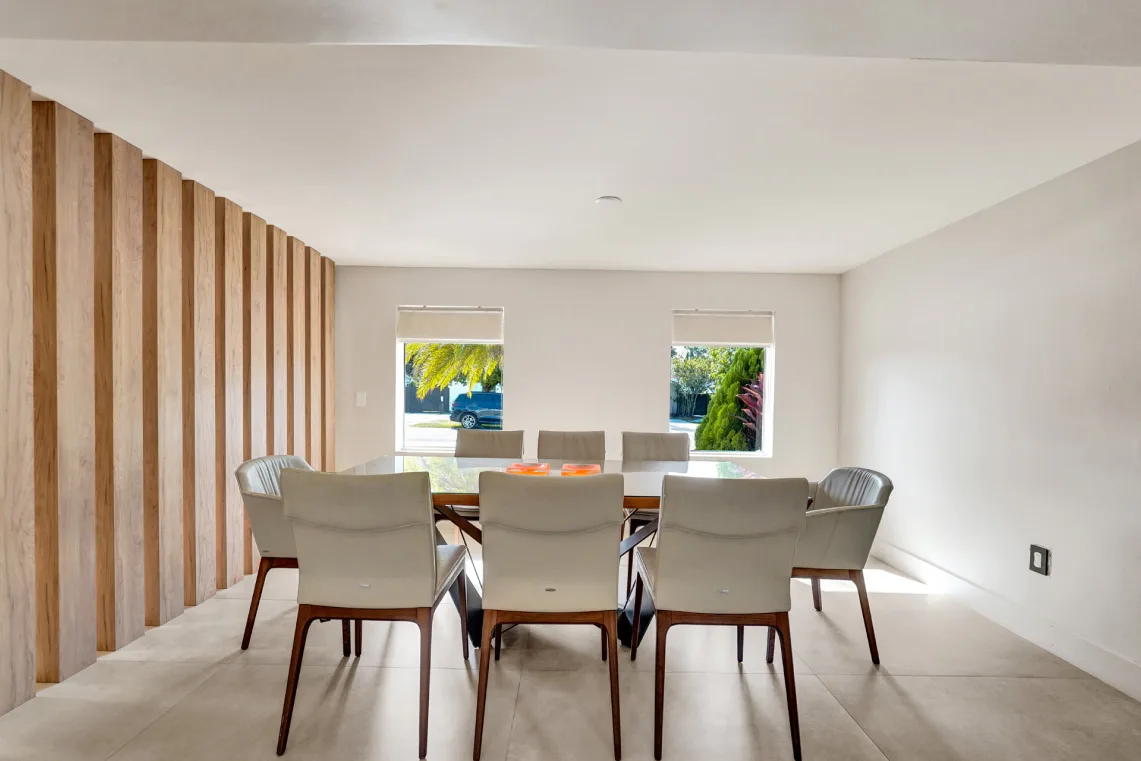 Dining room with glass table, leather chairs, and vertical wood-slat accent wall