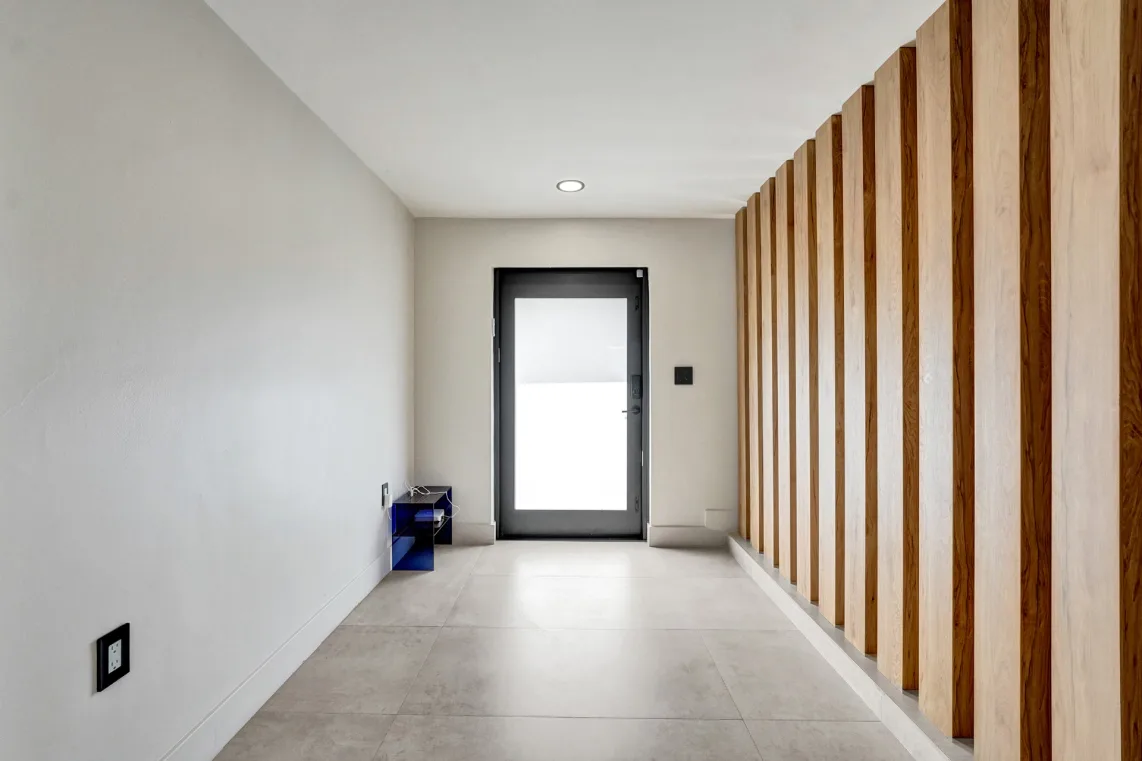 Entry foyer with frosted-glass front door and vertical wood-slat accent wall