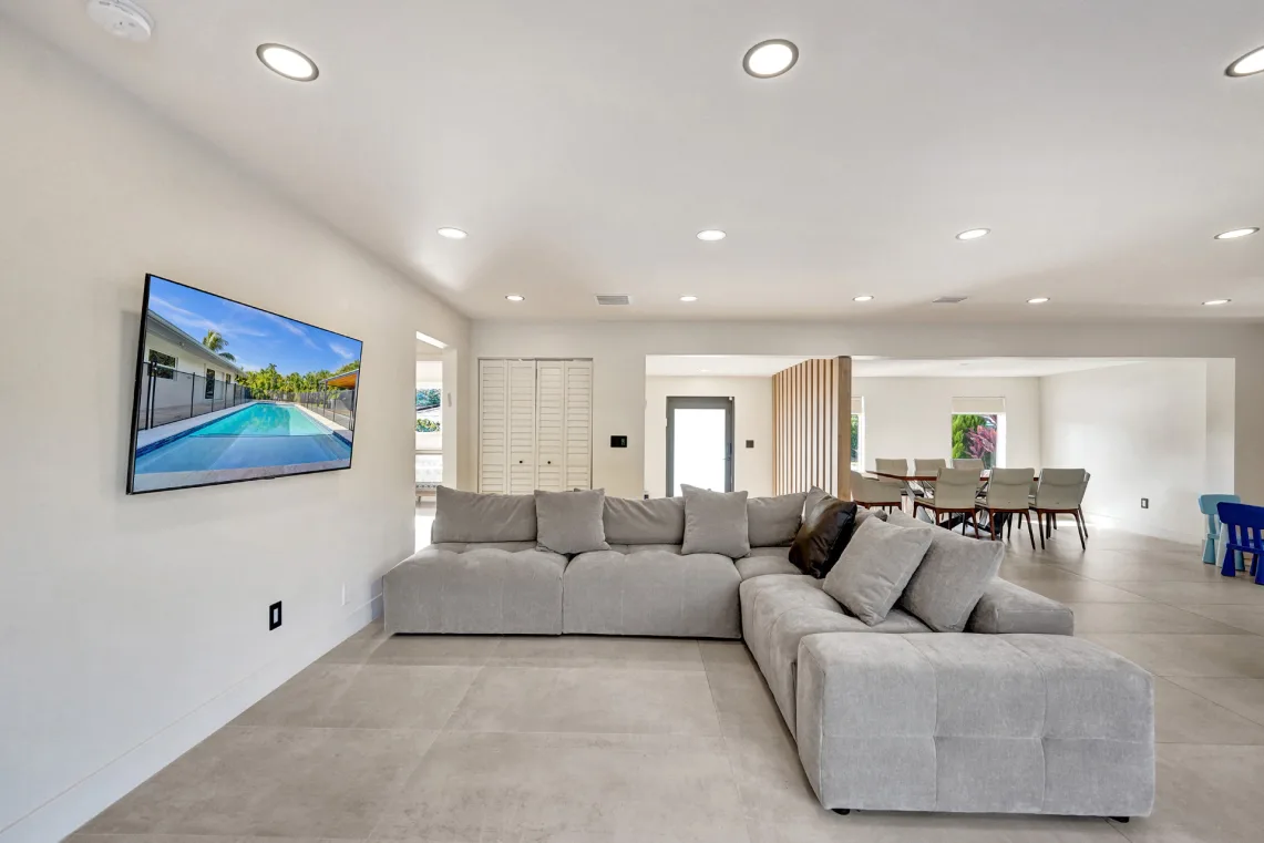 Large great room with gray sectional flowing into a bright dining area