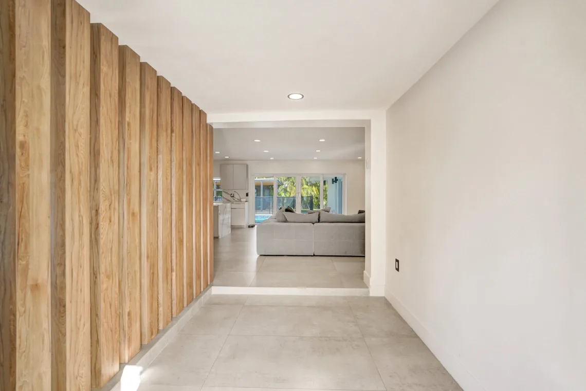 Hallway with vertical wood-slat feature wall leading to open living and kitchen area