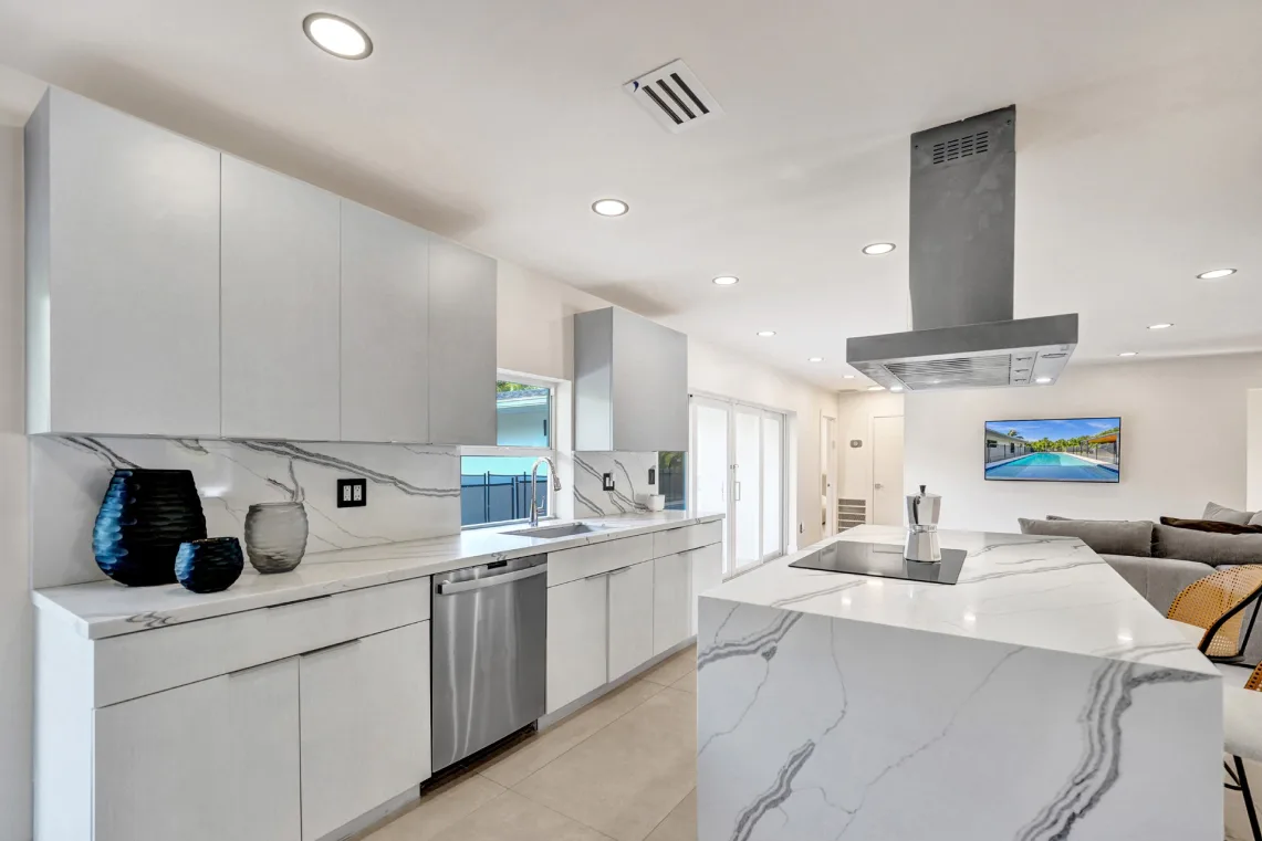 White kitchen with dramatic marble backsplash, waterfall island, and stainless appliances
