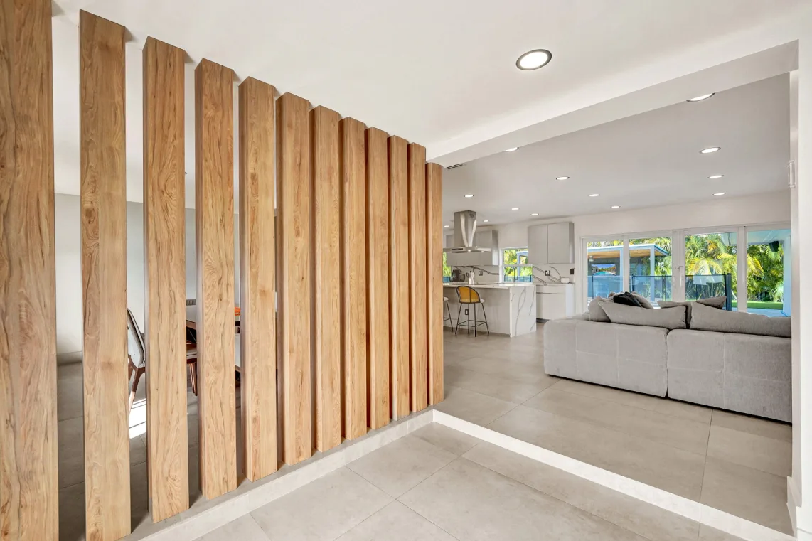 Living room with wood-slat partition, gray sectional, and open kitchen beyond