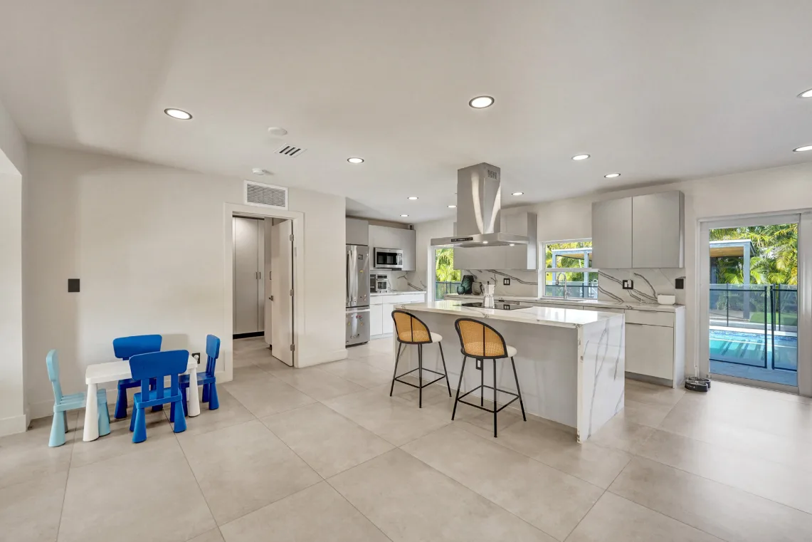Open great room with modern kitchen island, bar seating, and children's play area