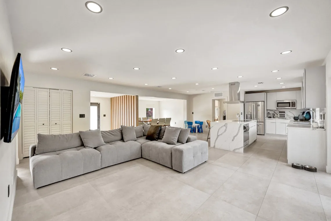 Expansive open living area connecting sectional lounge, dining, and white kitchen