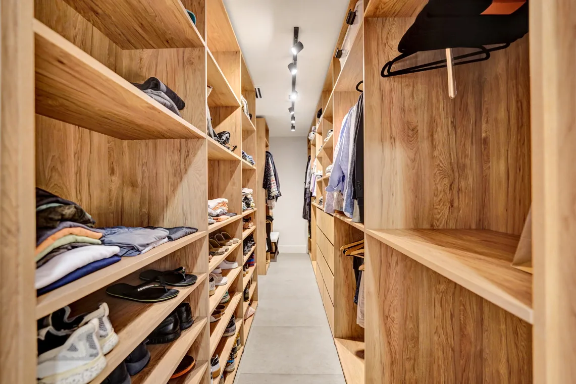 Custom wood walk-in closet with open shelving, shoe racks, and hanging rods